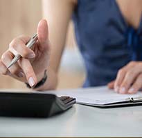 thumbnail image of girl with calculator adding up figures from data sheet to signify annual accounts and audit