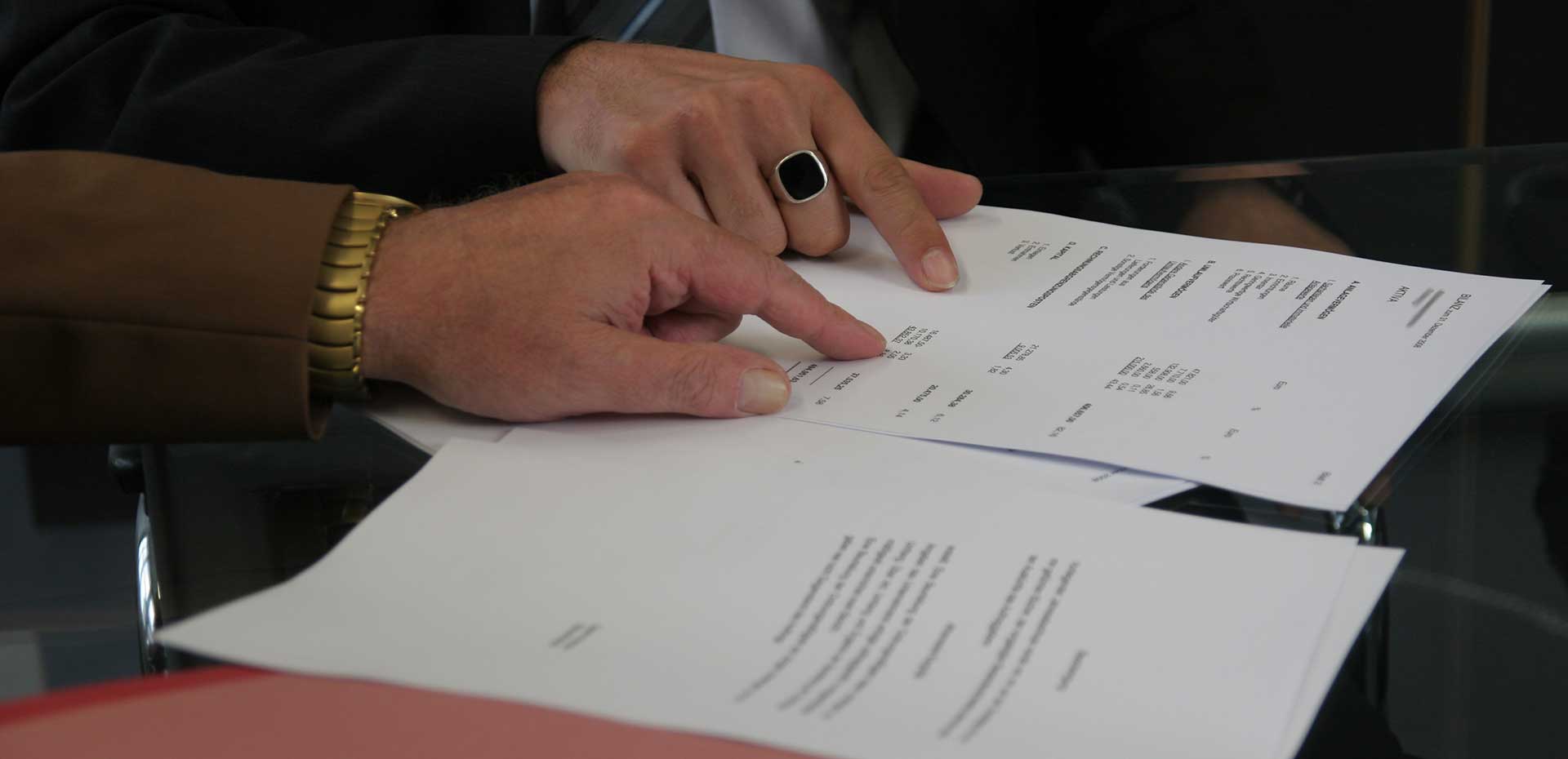 Image showing one hand of two different men pointing at items on profit and loss sheets